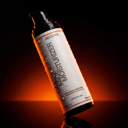 ASCEND Daily Face Moisturizer bottle with water droplets against a dark, orange-lit background. Paraben-free, vegan, with natural ingredients.