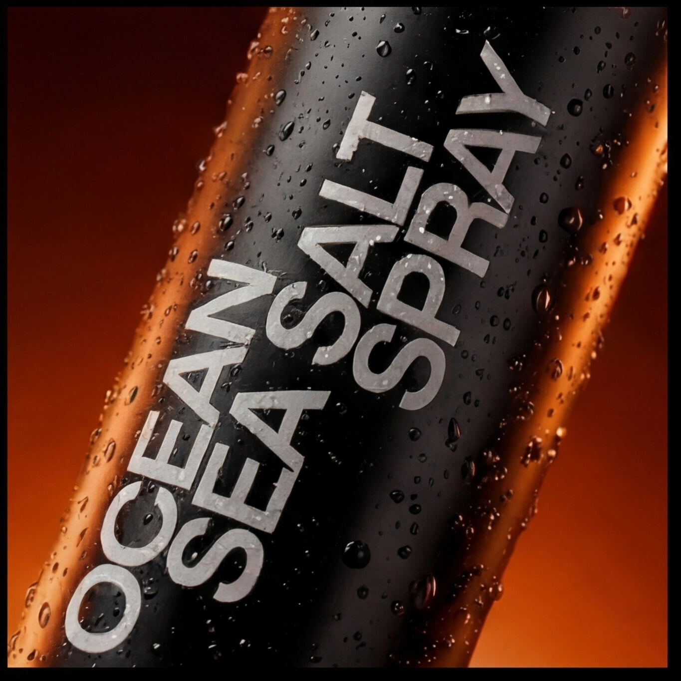 Macro shot of ASCEND Ocean Salt Sea Spray bottle label with water droplets on an orange-lit dark background.